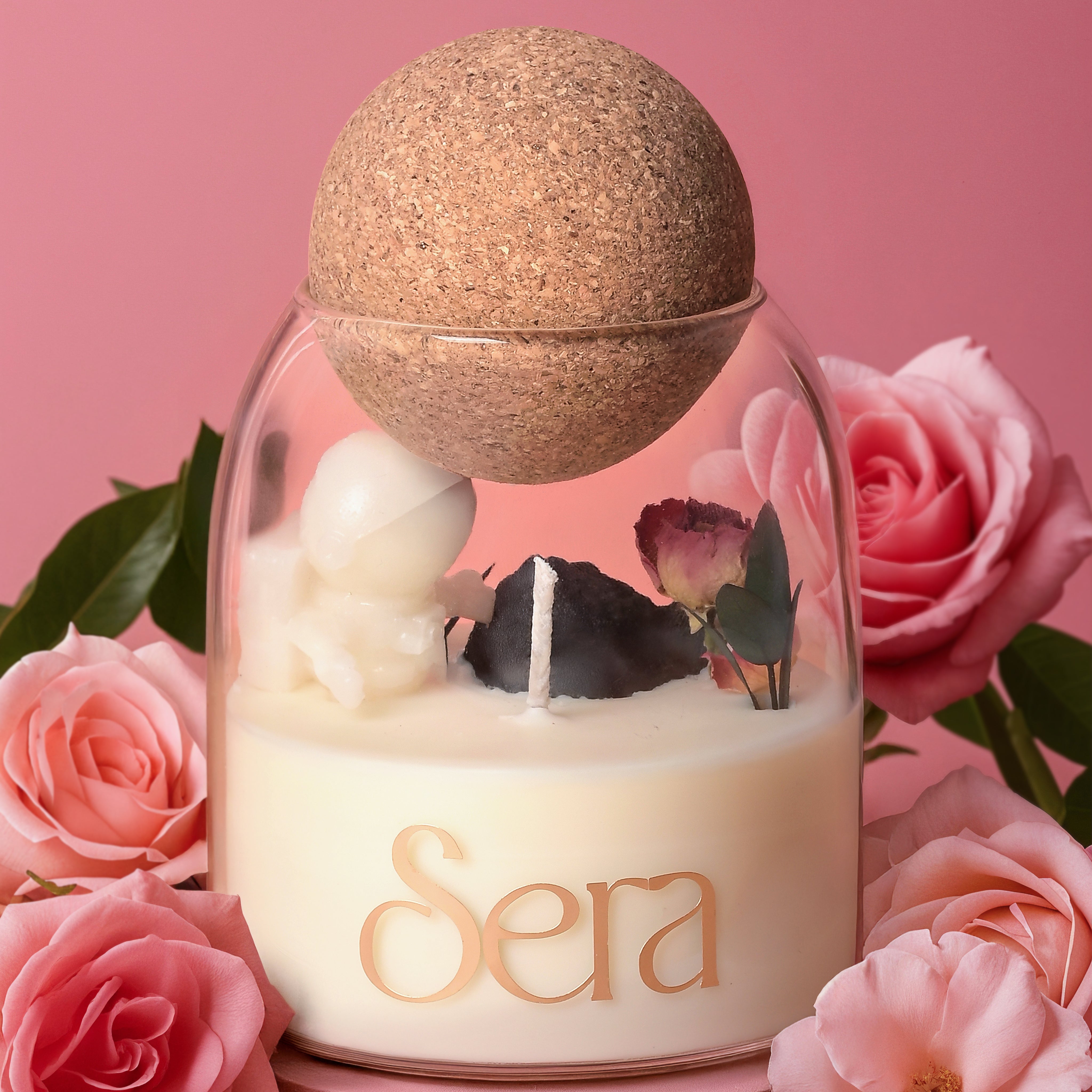 Candle in a glass jar with cork lid, surrounded by pink roses on a pink background